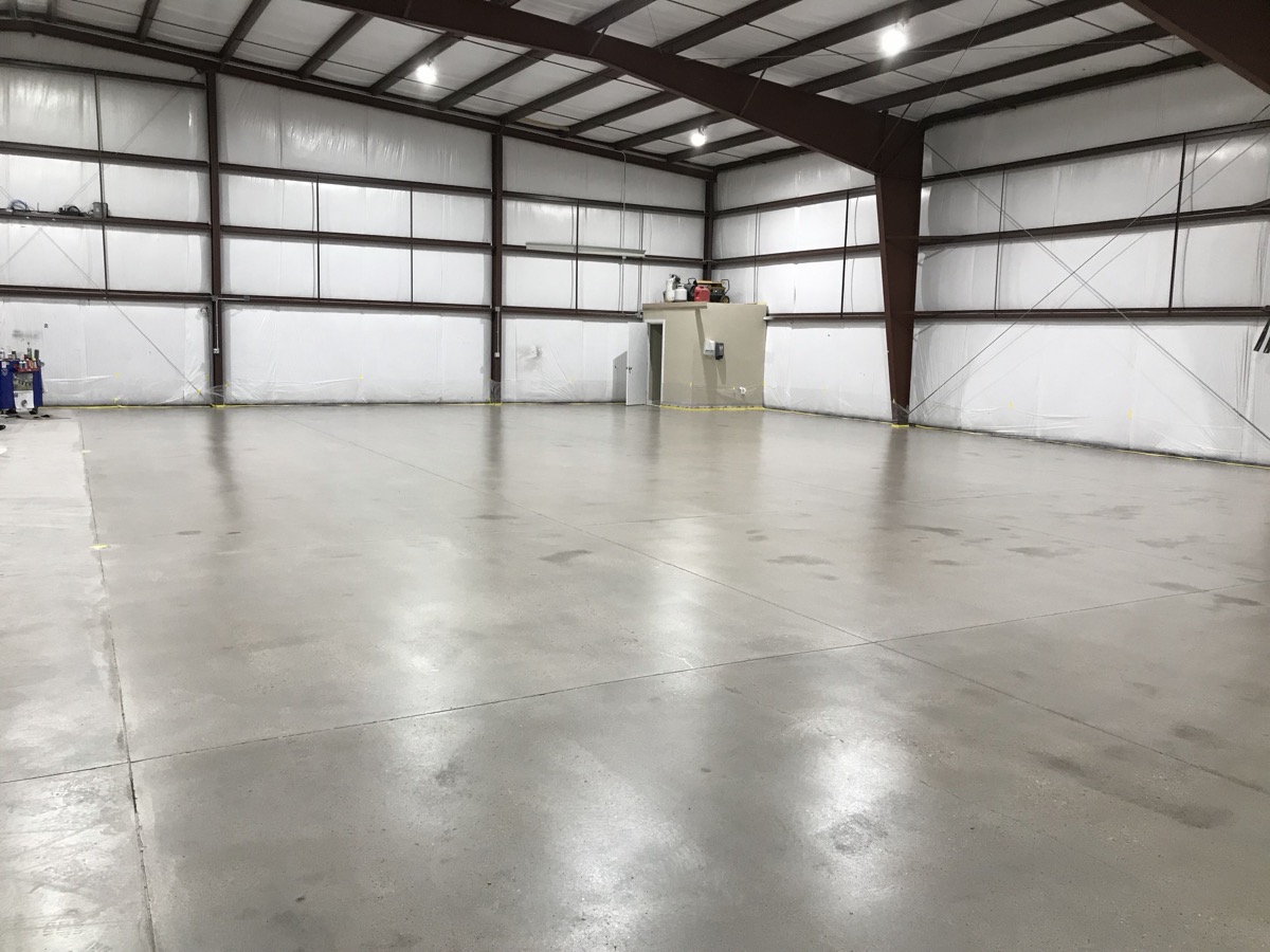 High-gloss polished concrete floor in a large aircraft hangar