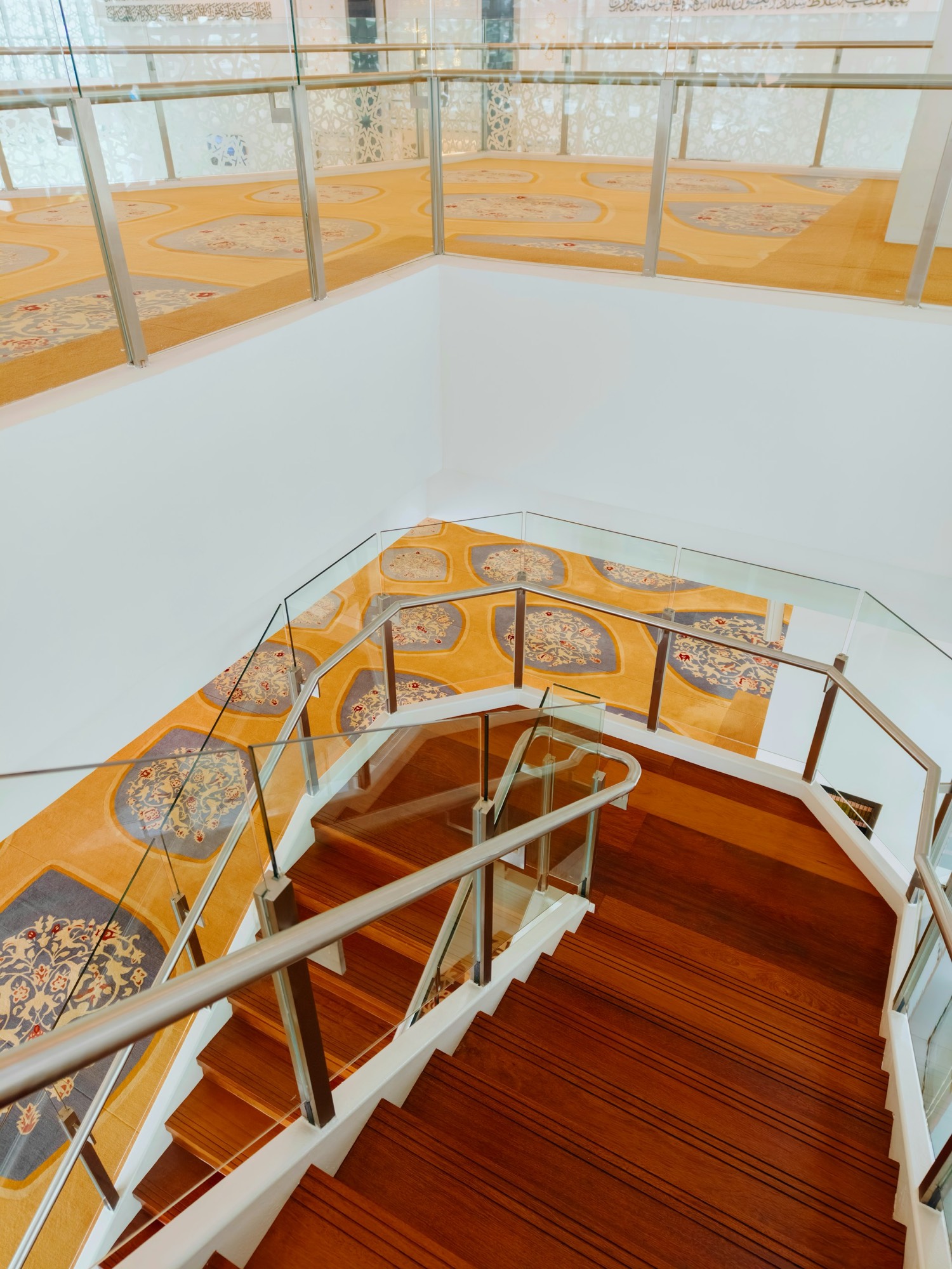 Carpeted staircase with glass railing